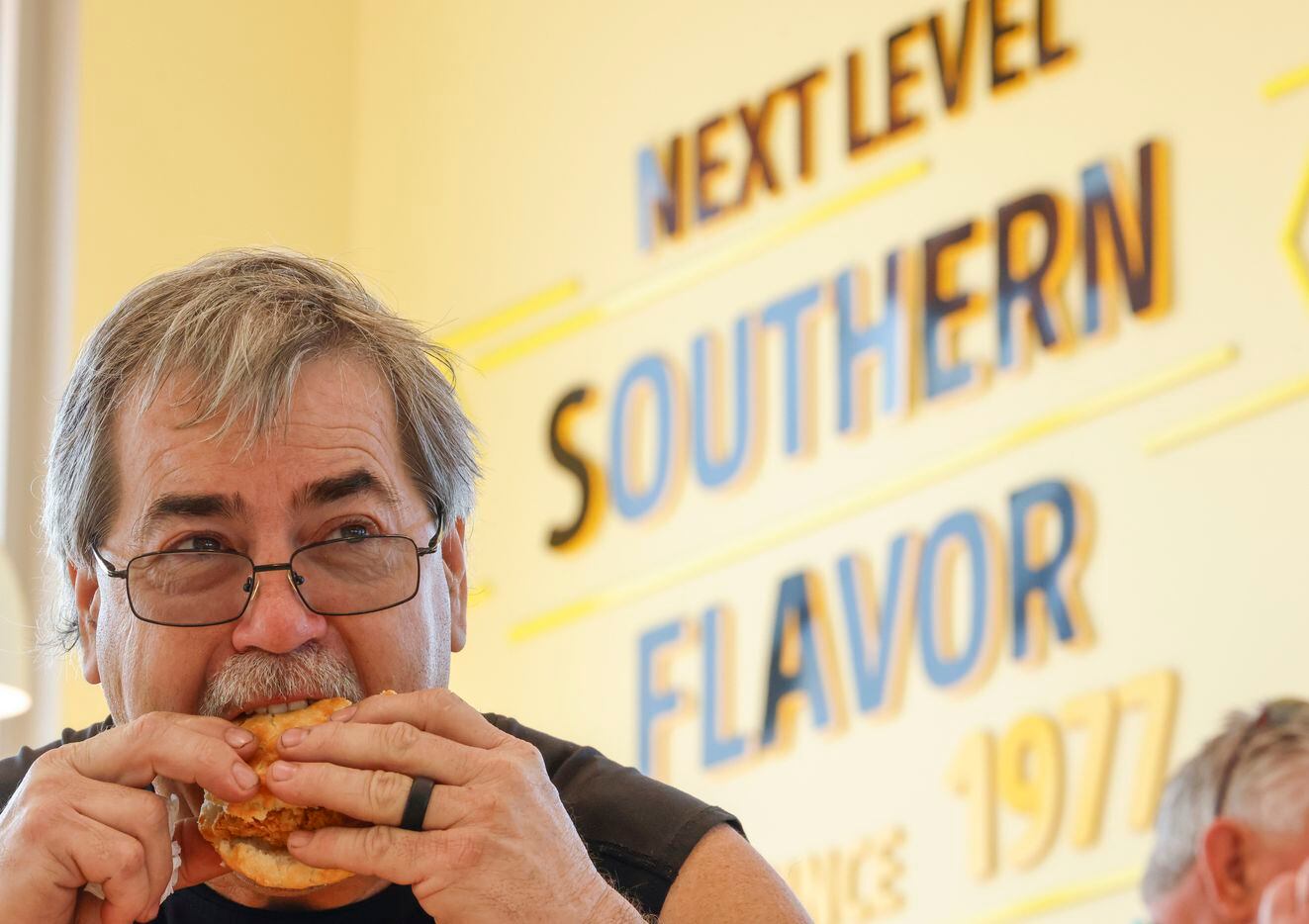 Richard Painter takes a bite of his biscuit during the opening day of Bojangles in Euless on...