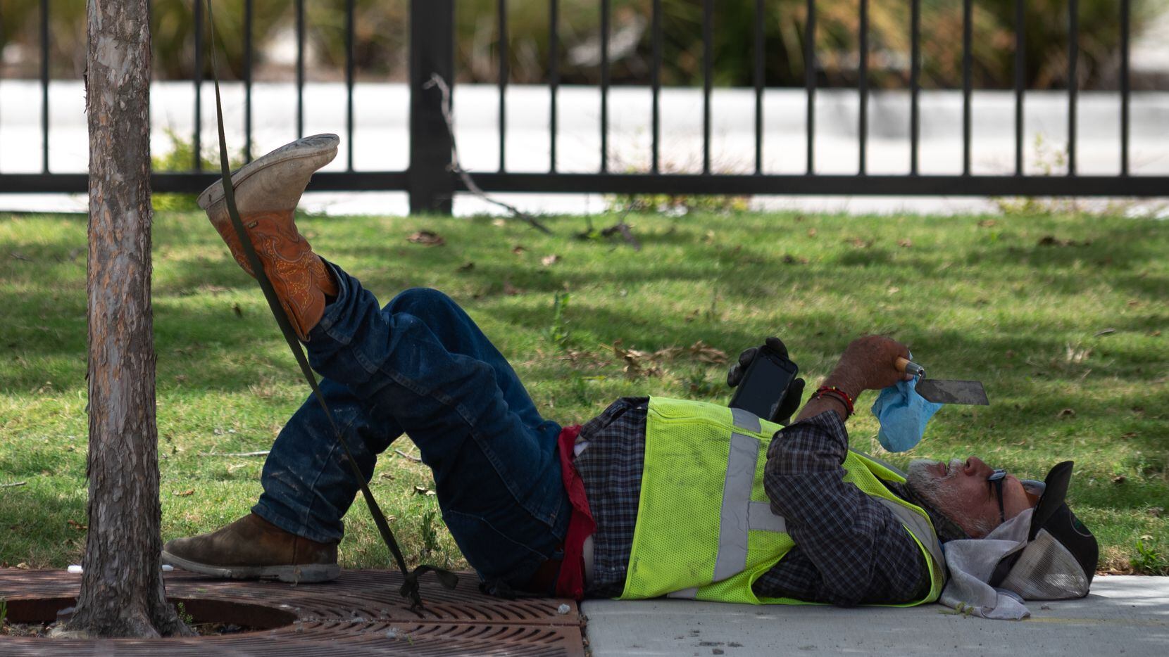 A man rests under the shade of a tree while working on Haskell Avenue between Live Oak...