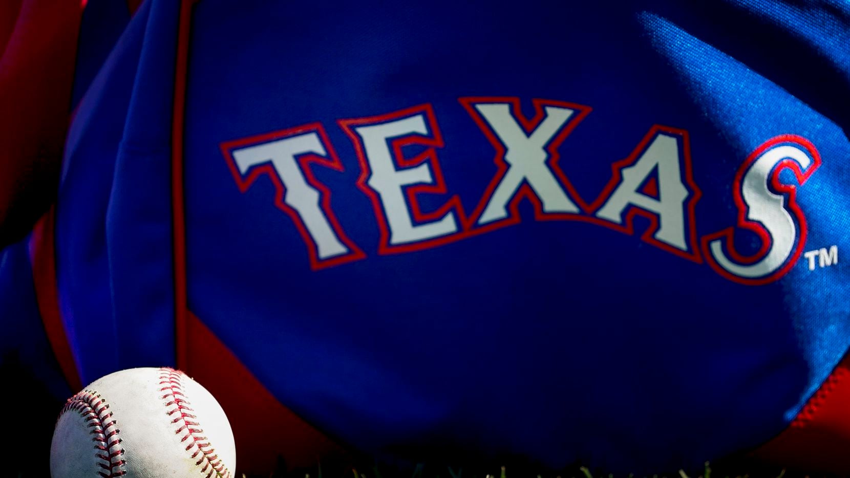 A baseball rests next to a playerÕs bag during a Texas Rangers spring training workout at...
