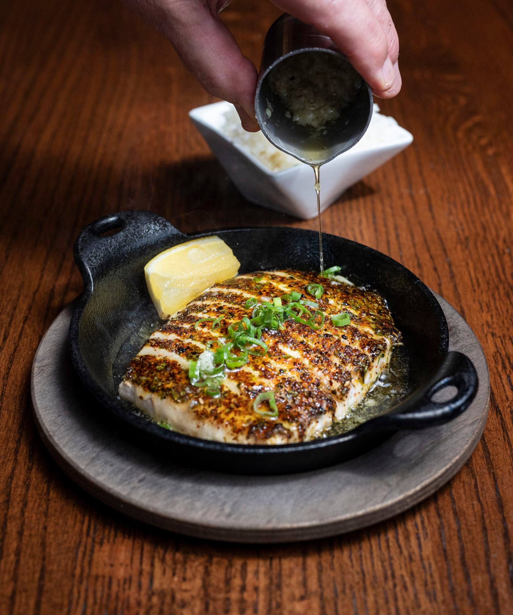 Pour garlic butter on the Cast Iron Swordfish dish with ginger and lemongrass from Shinsei restaurant in Dallas.