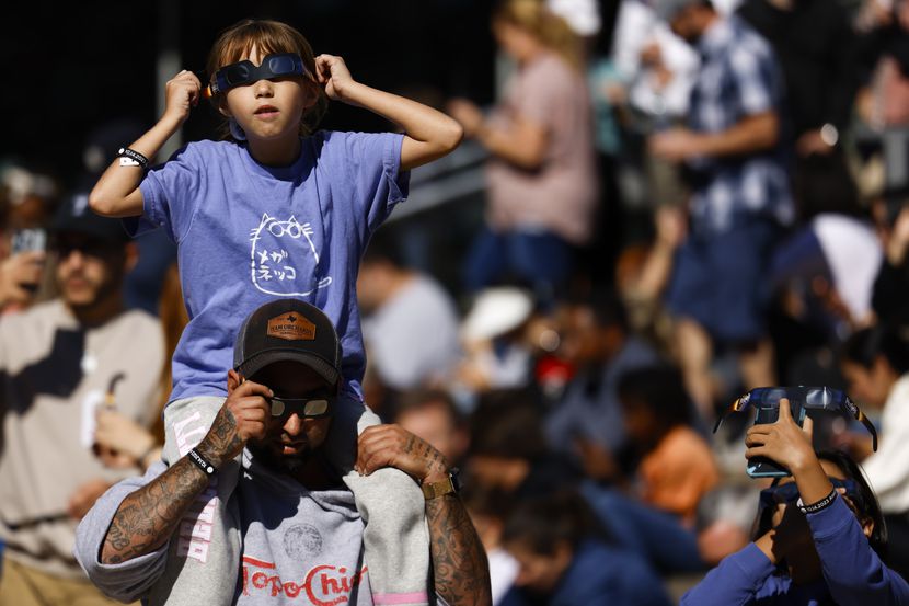 William Casarez carrying his daughter Brianna, 9, watch the annular solar eclipse on...