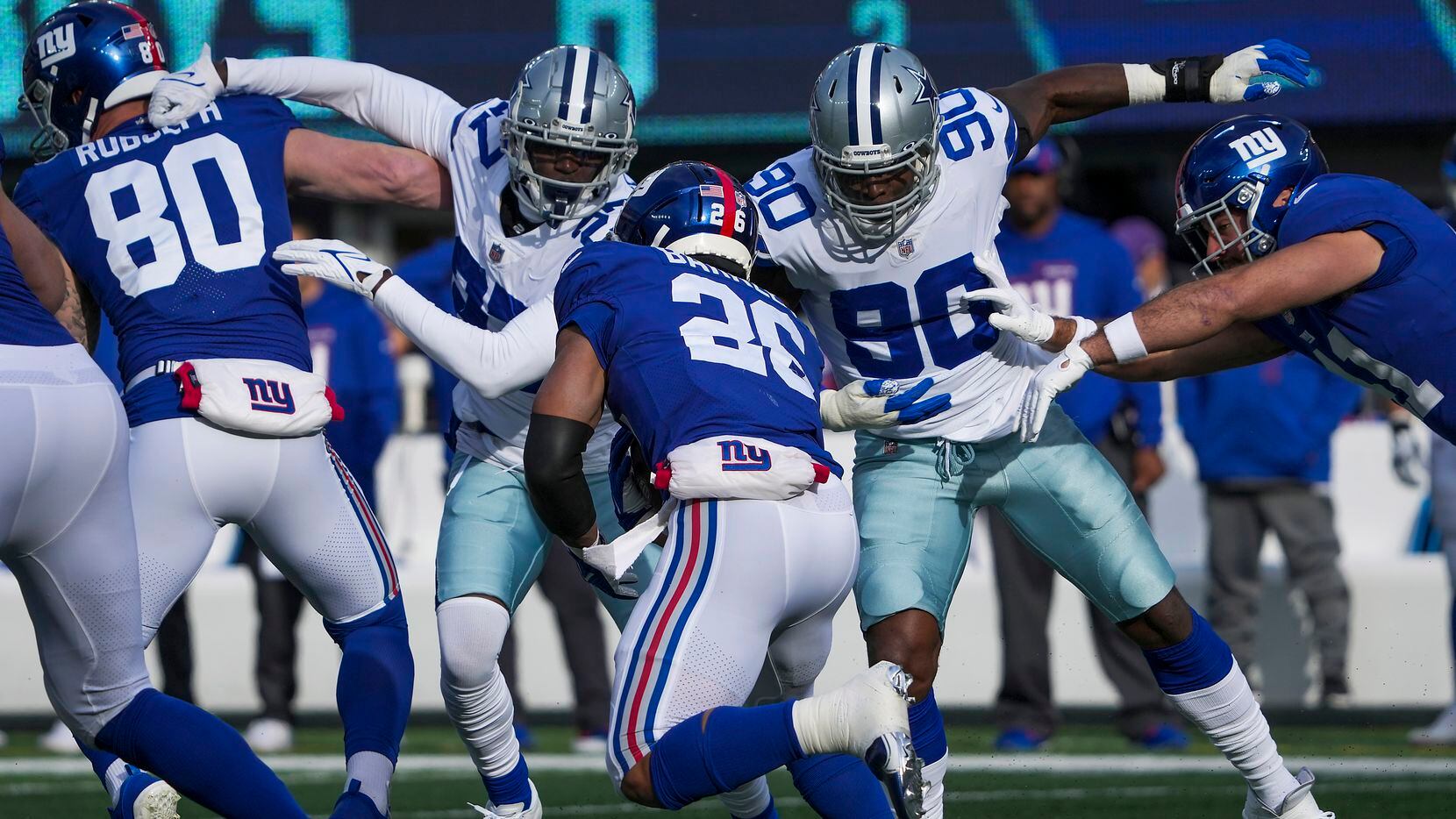 Dallas Cowboys defensive end Demarcus Lawrence (90) and safety Jayron Kearse (27) move in for a tackle on New York Giants running back Saquon Barkley (26) during the first half of an NFL football game on Sunday, Dec. 19, 2021, in East Rutherford, N.J.