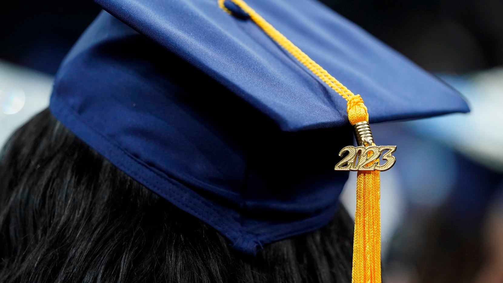 FILE - A tassel with 2023 on it rests on a graduation cap as students walk in a procession...