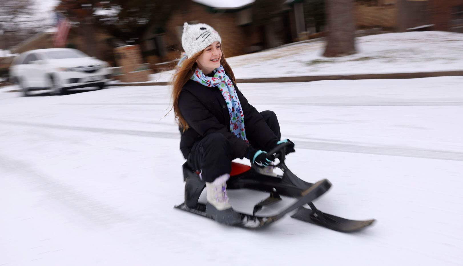 Julia Schack sleds down an icy street in N. Arlington, Texas, after a band of sleet dropped...