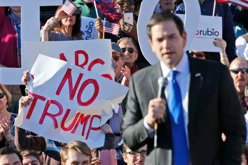 Simpatizantes del candidato Marco Rubio sostienen pancartas de repudio a su rival Donald...
