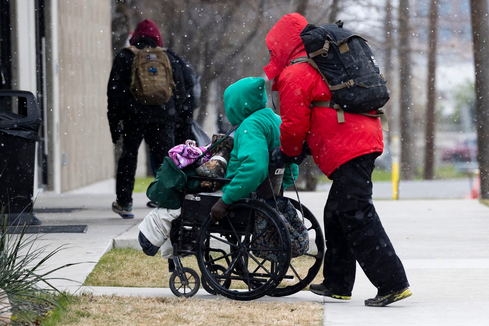 People make their way to Austin Street Center for warmth as snow falls on Thursday, Dec. 22,...