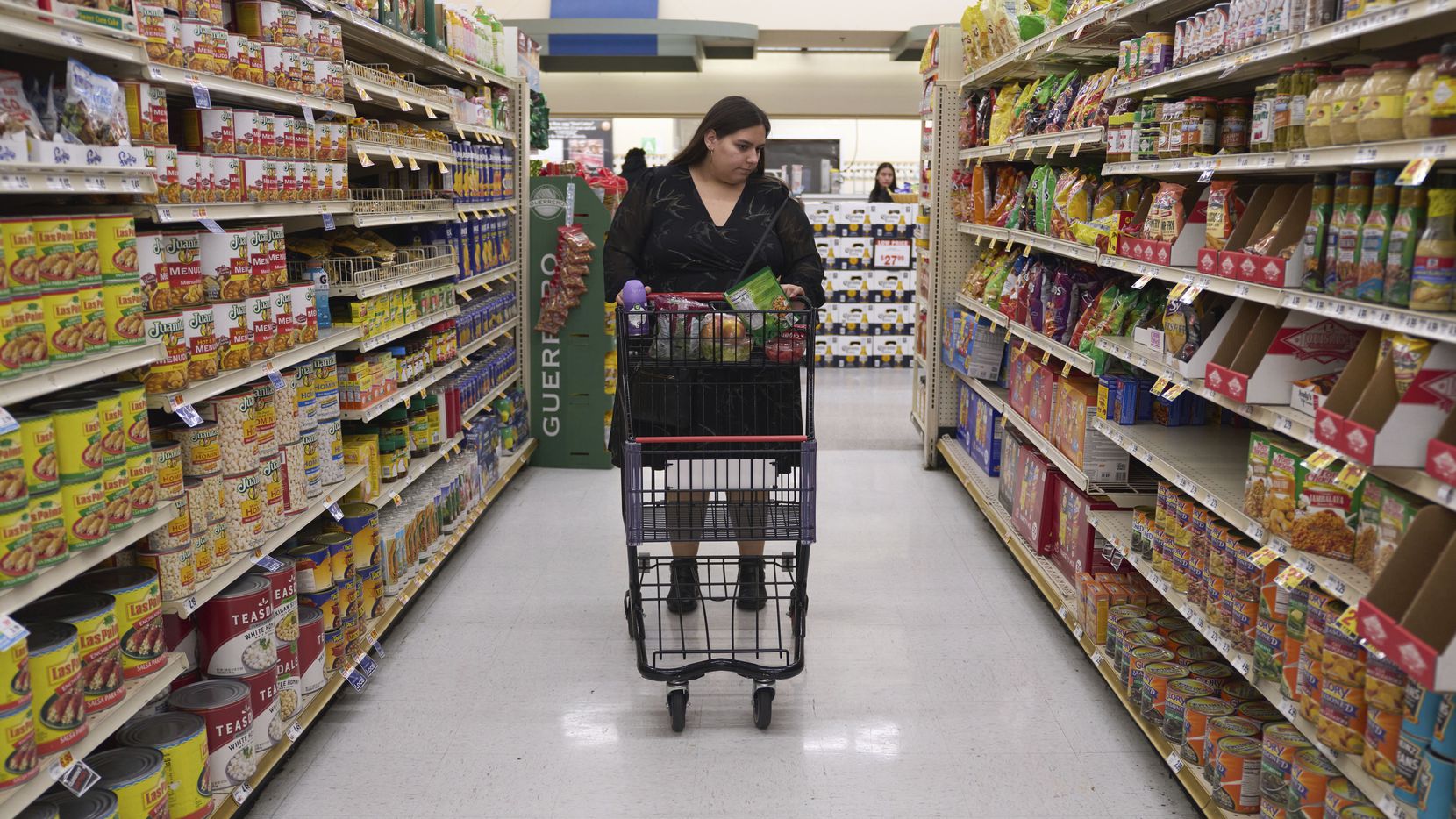 Jaqueline Benitez pushes her cart down an aisle as she shops for groceries at a supermarket...