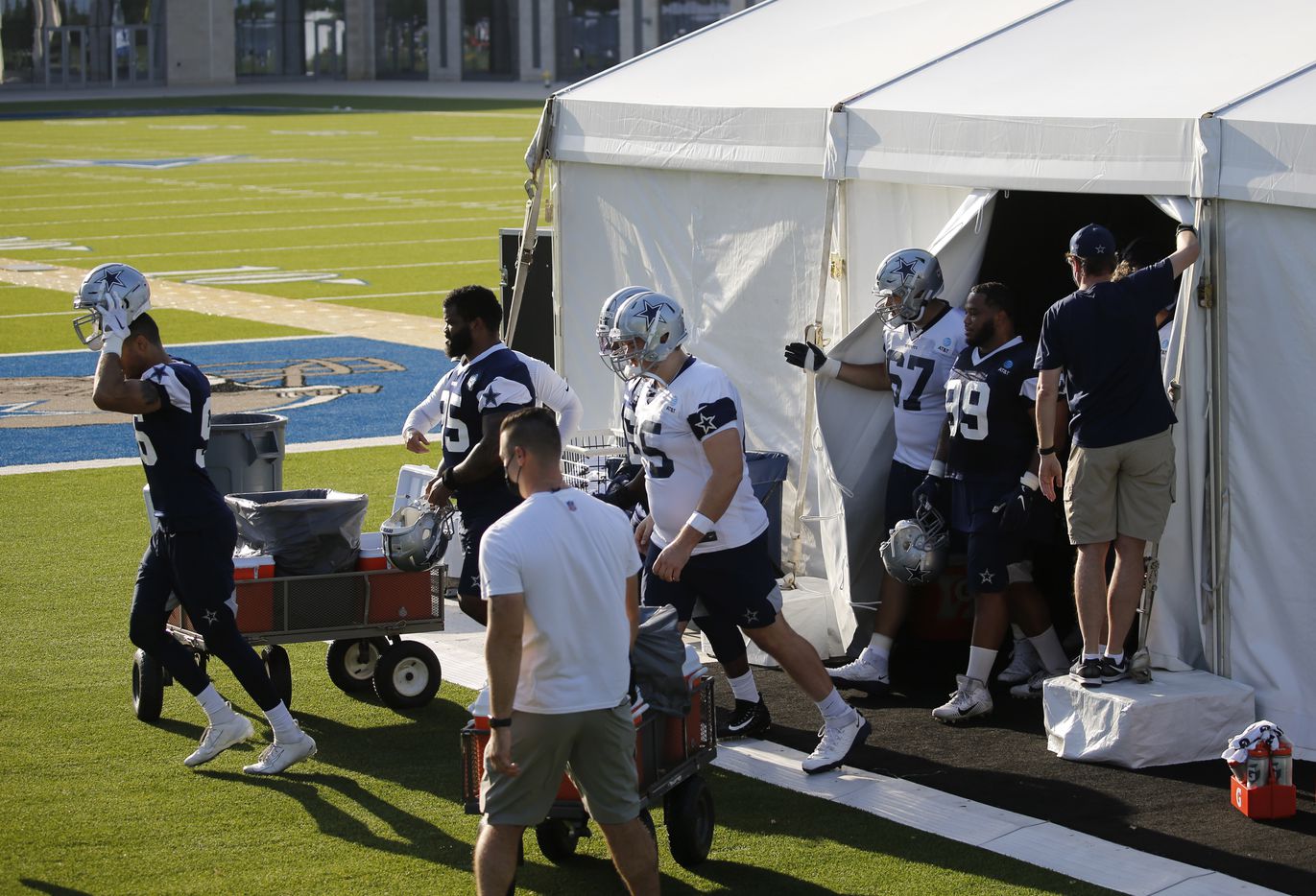 Dallas Cowboys players make their way out of an air conditioned tent for the next stage of...