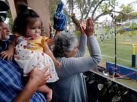 Robert Acosta holds 10-month old Jessica Rodriguez Mala as his mother, Adela Acosta, cheers...