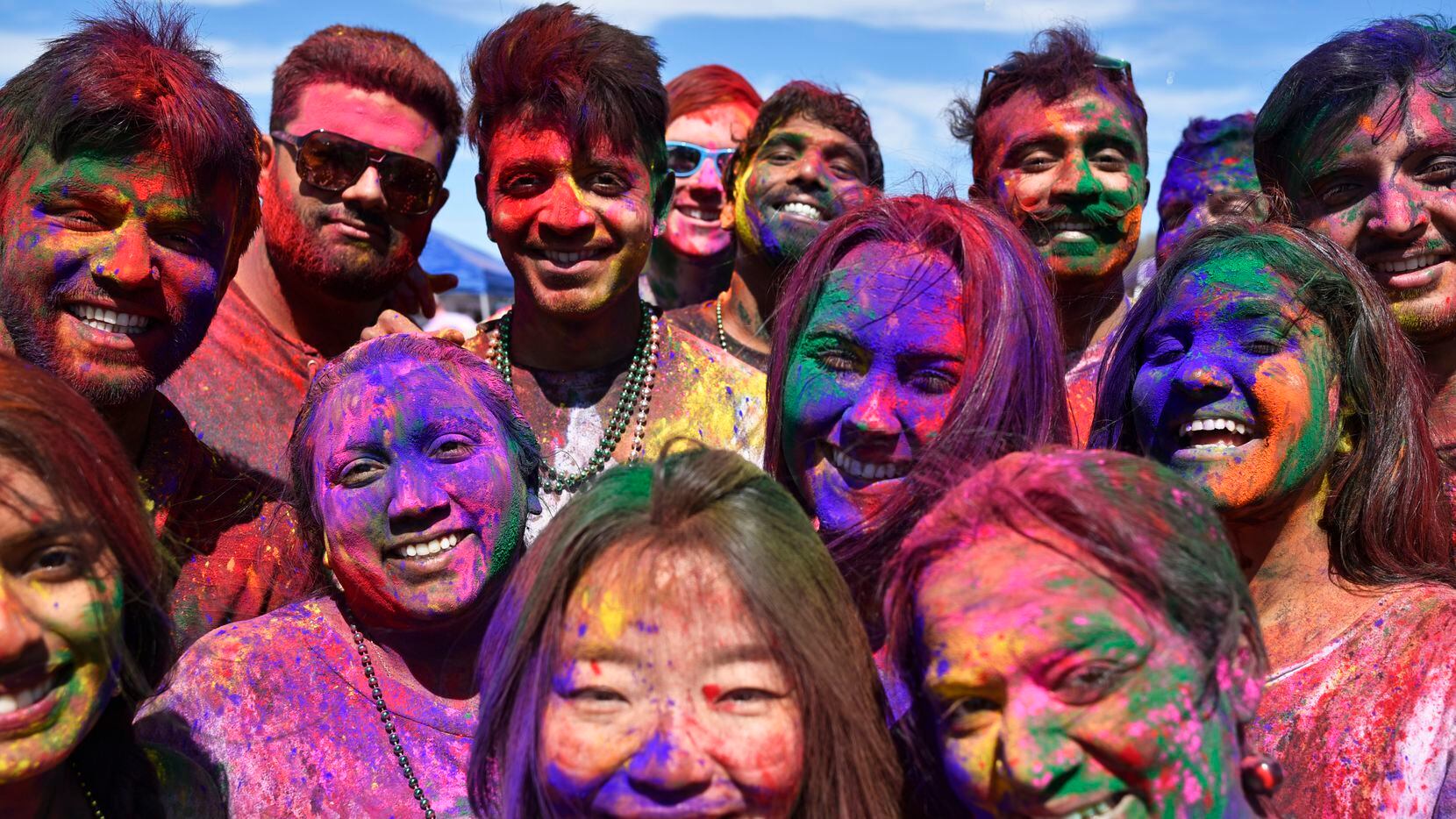Festival goers celebrate Holi with colored pigment on their face and bodies during the...
