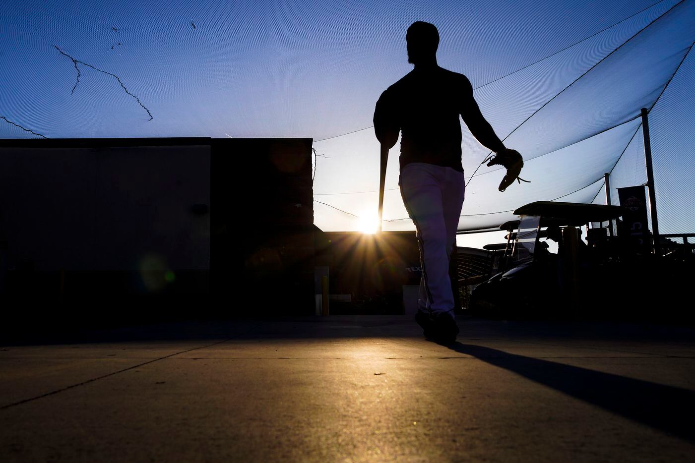 Texas Rangers infielder Sherten Apostel walks from the team clubhouse as the sun rises...