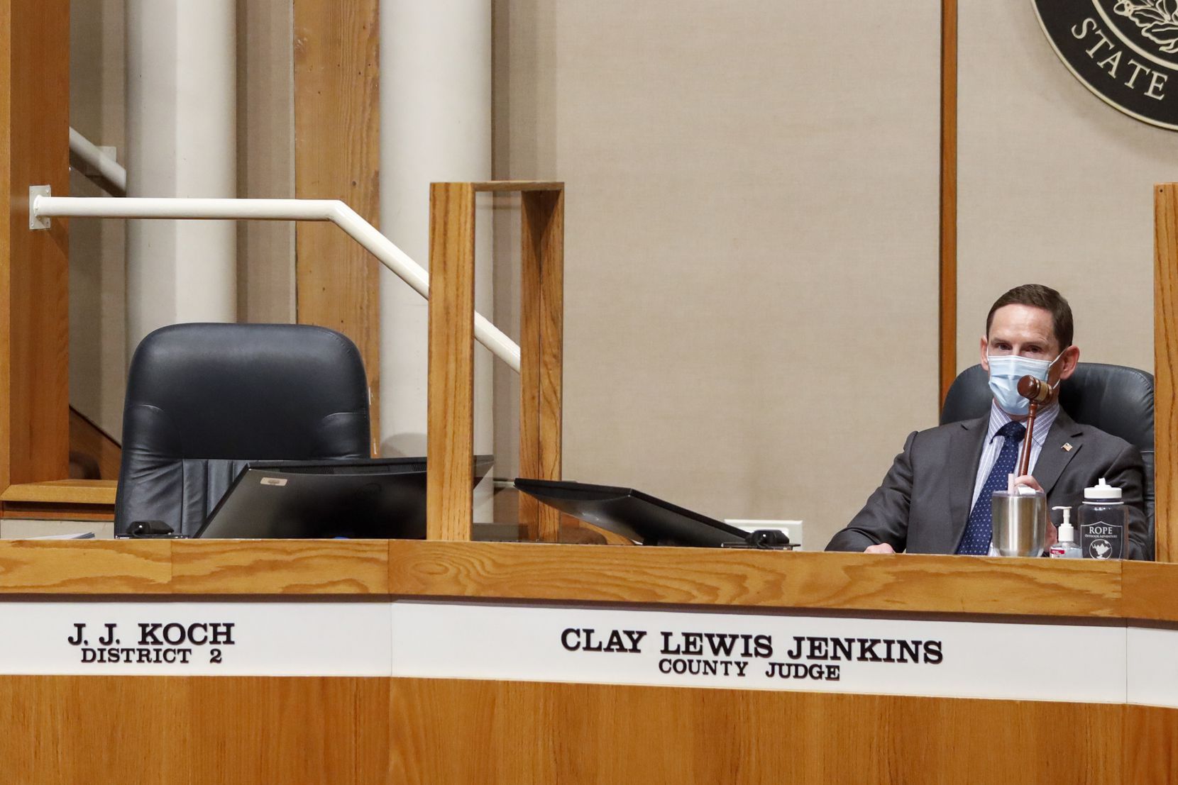 Dallas County Judge Clay Jenkins banged a gavel next to the empty seat of Dallas County Commissioner J.J. Koch during a commissioners court meeting Tuesday. Earlier, Koch was escorted from the meeting for refusing to wear a mask. (Elias Valverde II/The Dallas Morning News)