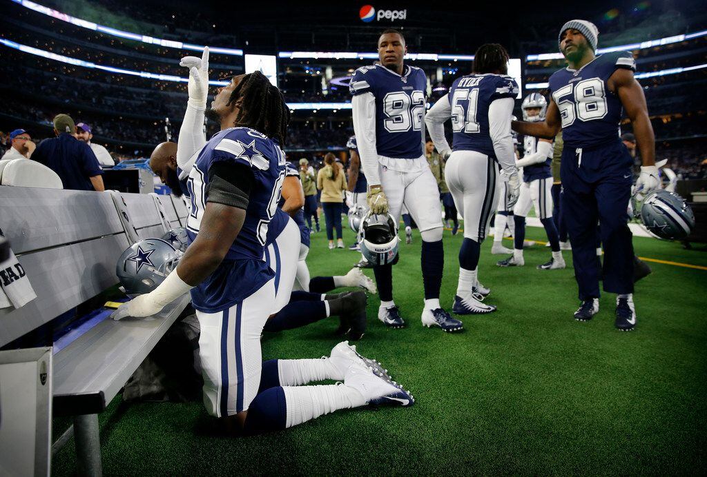 Dallas Cowboys defensive end Demarcus Lawrence (90) says a prayer on the bench before facing...