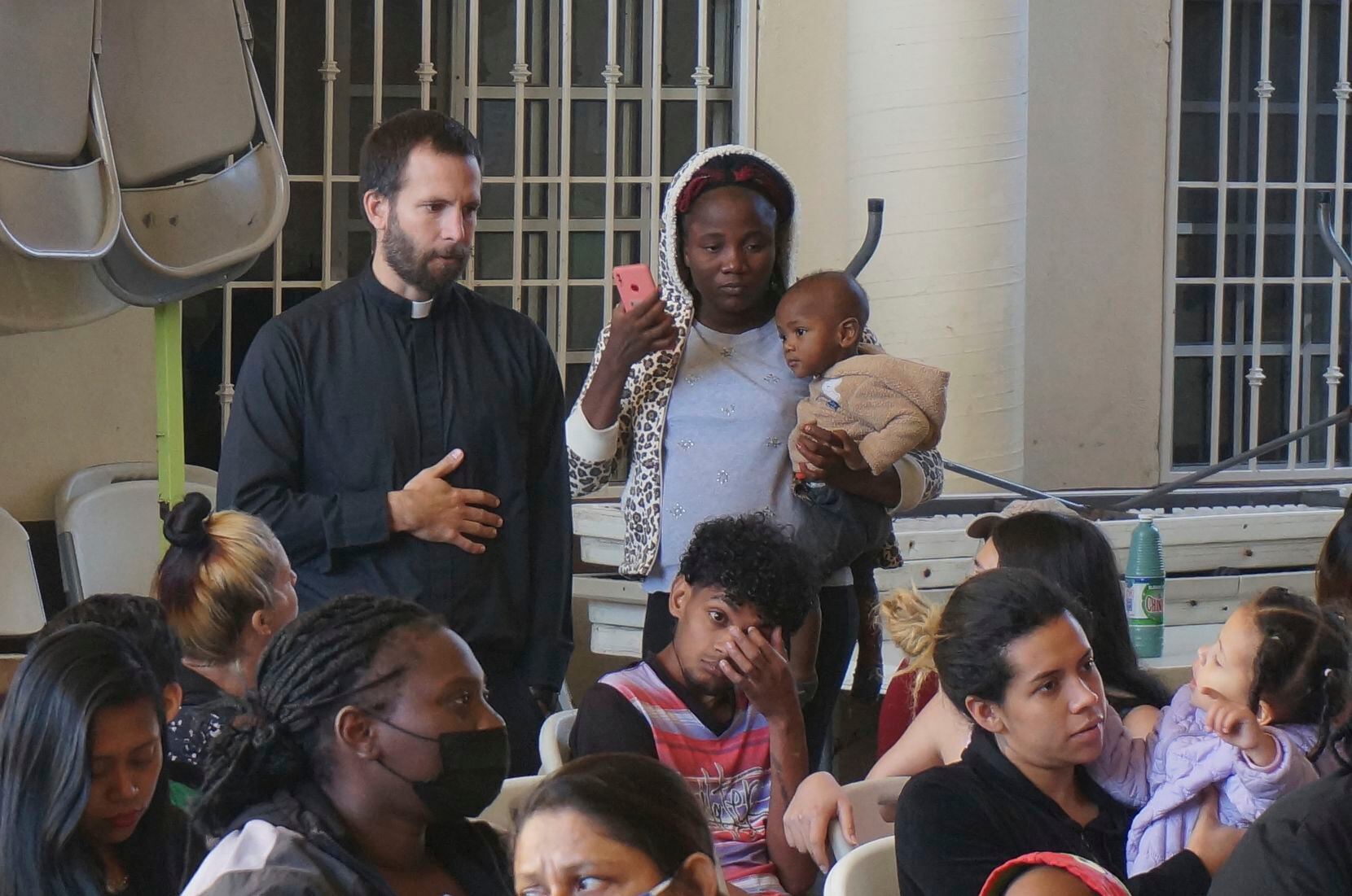 The Rev. Brian Strassburger, a Jesuit priest, talks with Rose, a Haitian migrant holding her...