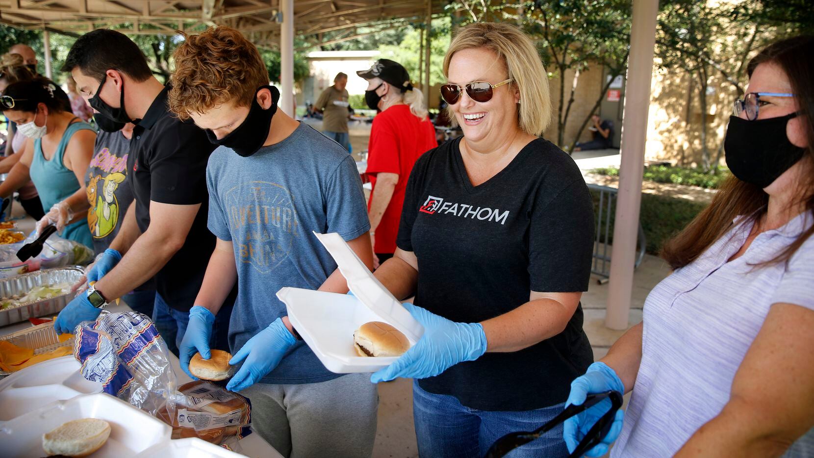 Agent Brandy Jett (center) prepares a hamburger along with her Fathom Realty family. They volunteer once a quarter for Bridging Hope Ministries in feeding the homeless. On Aug. 30, they were working outside the Denton Parks & Recreation building in Denton.