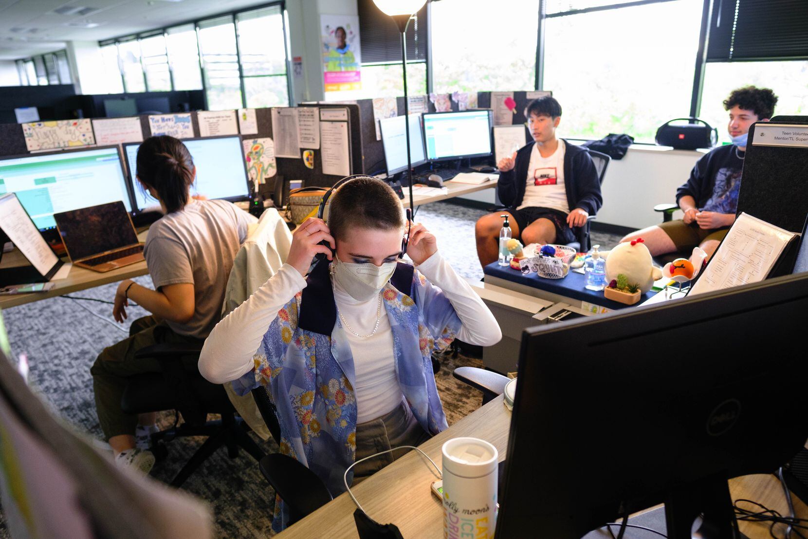 Vivian, a volunteer at Seattle's Teen Link dons a headset to take a call. She and three...