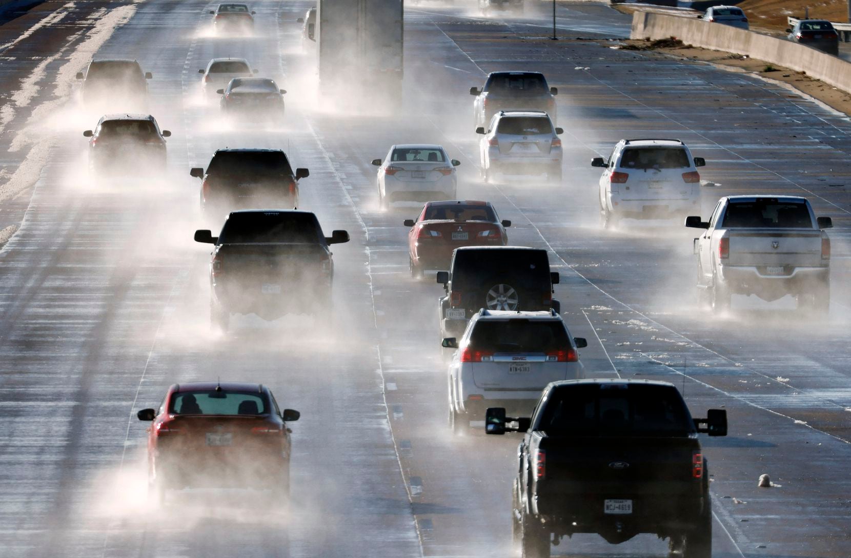 Water spray from melting sleet and snow trails vehicles traveling on westbound Interstate 30...