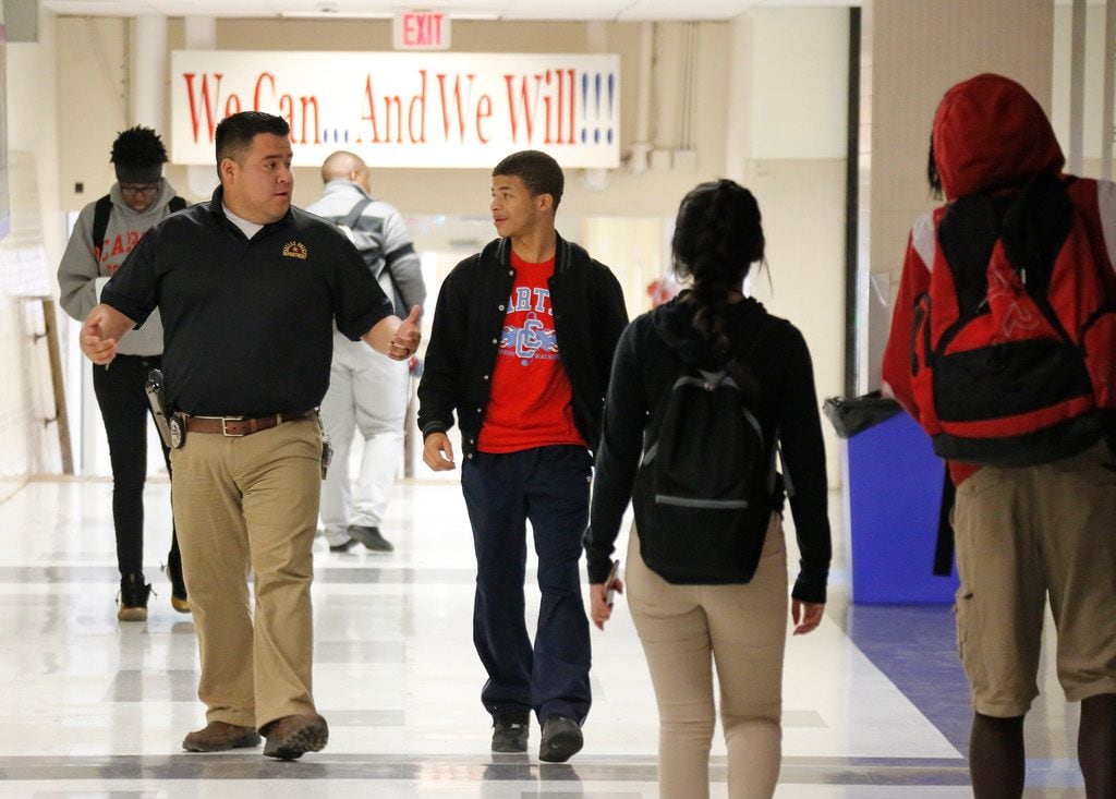 Dallas Police Officer Victor Guardiola (left) talks with Carter High School student Sedric...