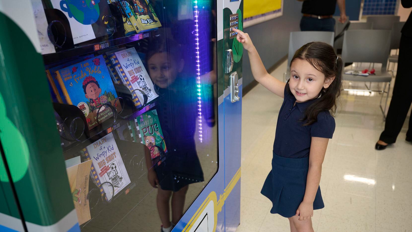 Kindergartner student Clarissa Alejandre uses a book vending machine that was donated to the...