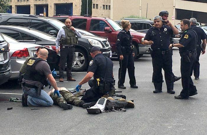 Los oficiales de policía atienden a un hombre al que derribaron después de que disparó al...