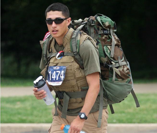 Nicholas Anderson of Arlington carries a backpack filled with empty ammo cans and camping...