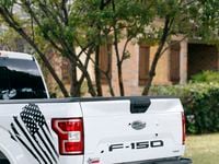 Bullet holes in the tailgate of a Ford F-150 pickup are pictured next door to the initial...