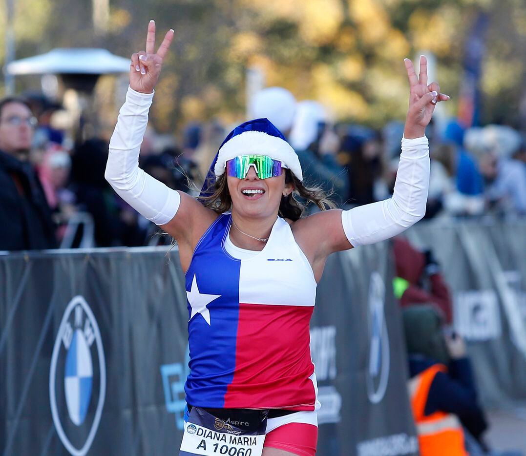 Diana Sterling of Rockwall crosses the half marathon finish line wearing a Texas Flag and a...