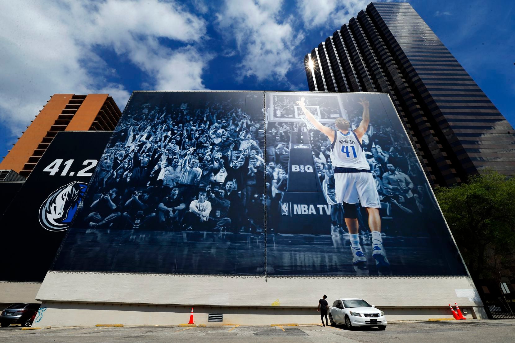 A young man stands by a 68-by-193-foot mural of Dallas Mavericks forward Dirk Nowitzki...