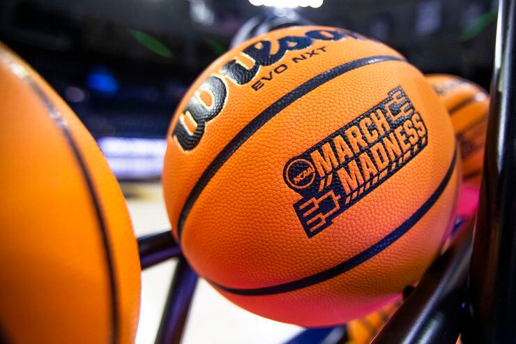 FILE - A basketball with a March Madness logo rests on a rack before a First Four game...