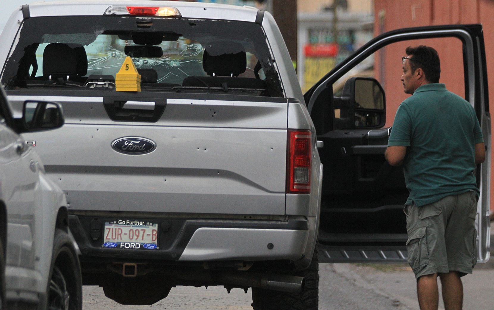 A person on Avenida Tecnológico in Ciudad Juárez inspects a pickup showing the impact of...