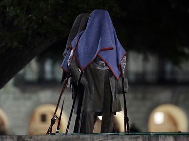 Confederate statutes removed from the University of Texas are covered and secured to a...