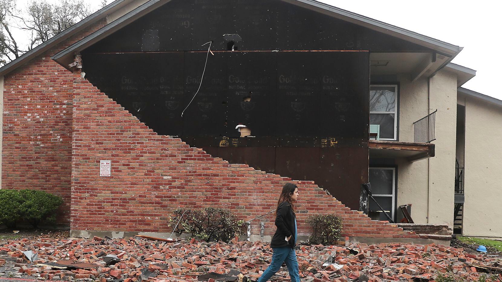 A resident walks past an apartment unit where the bricks fell off at Deer Park Apartments...