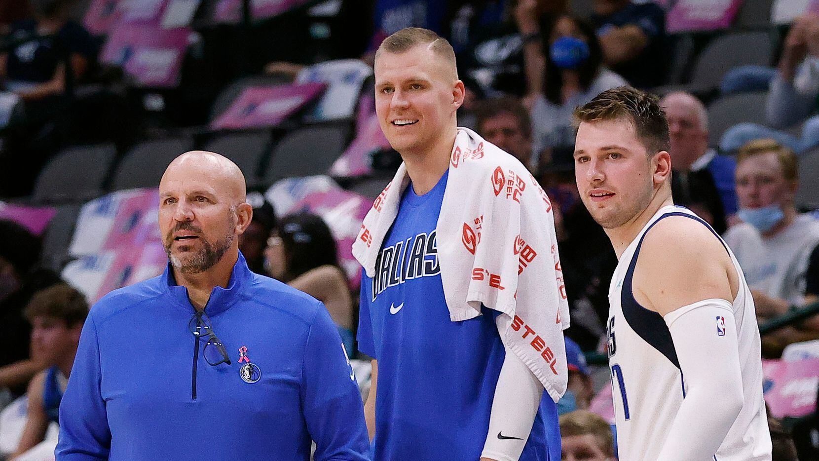 Dallas Mavericks head coach Jason Kidd, center Kristaps Porzingis (center) and guard Luka Doncic watch from the scorers table as the team competes against the Utah Jazz in the first half at the American Airlines Center in Dallas, Wednesday, October 6, 2021.