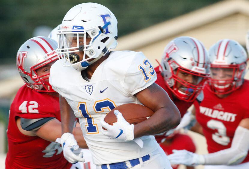 Frisco running back Blake May (13) runs away from a host of Dallas Woodrow Wilson defenders...
