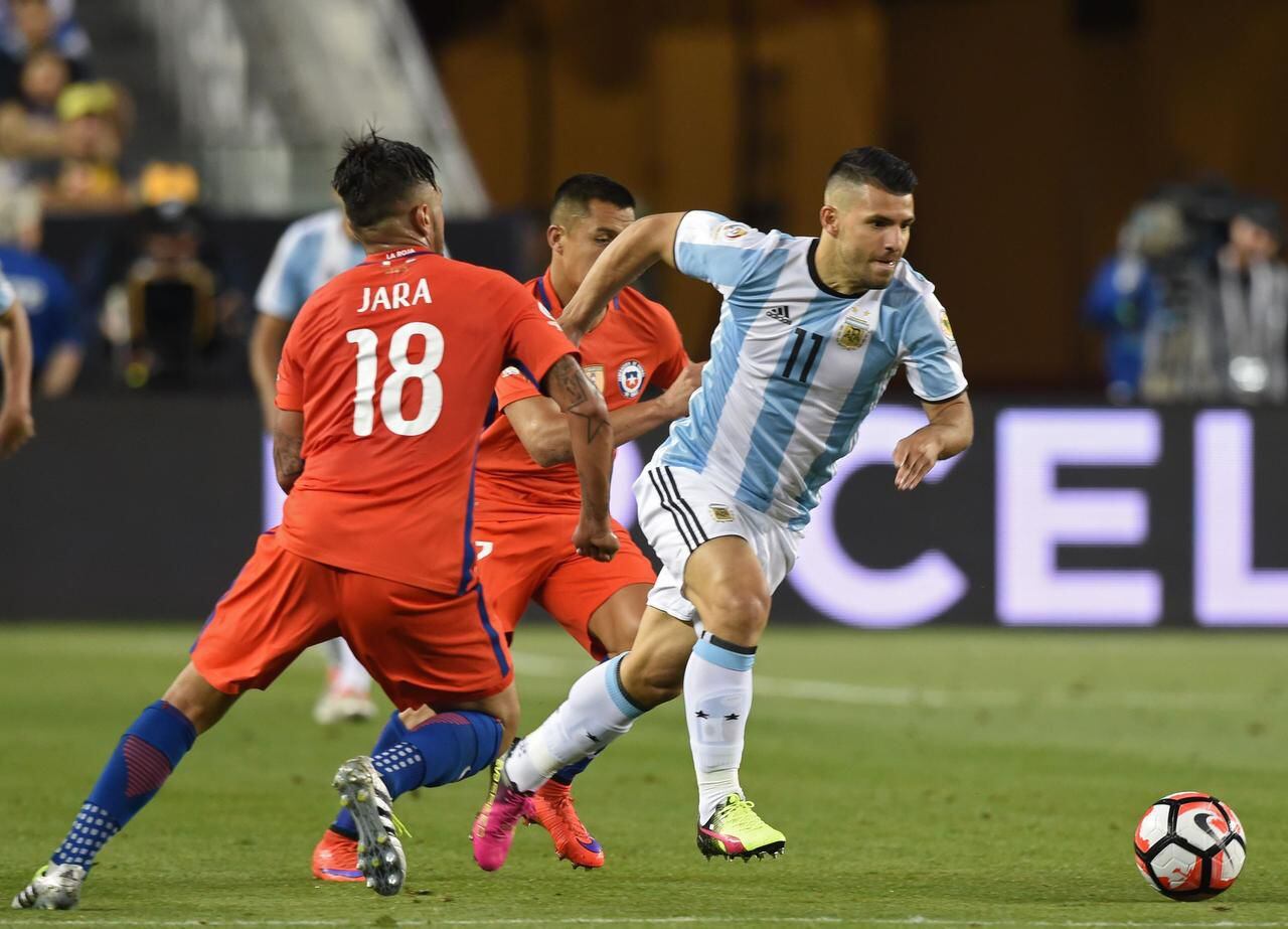 Sergio Agüero (11) conduce el balón ante la presión de Gonzalo Jara y Alexis Sánchez durante...