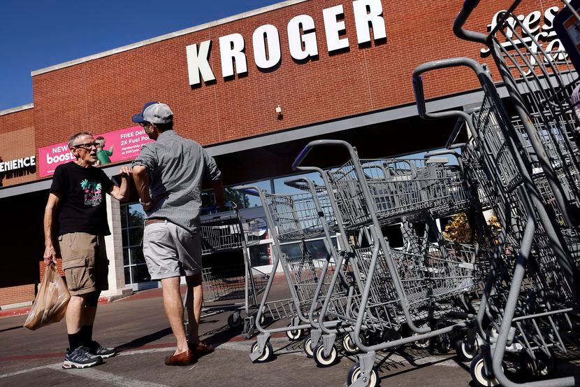 Shopper Jimmy Bartlett of Dallas (left) visits with a friend outside the Kroger grocery...