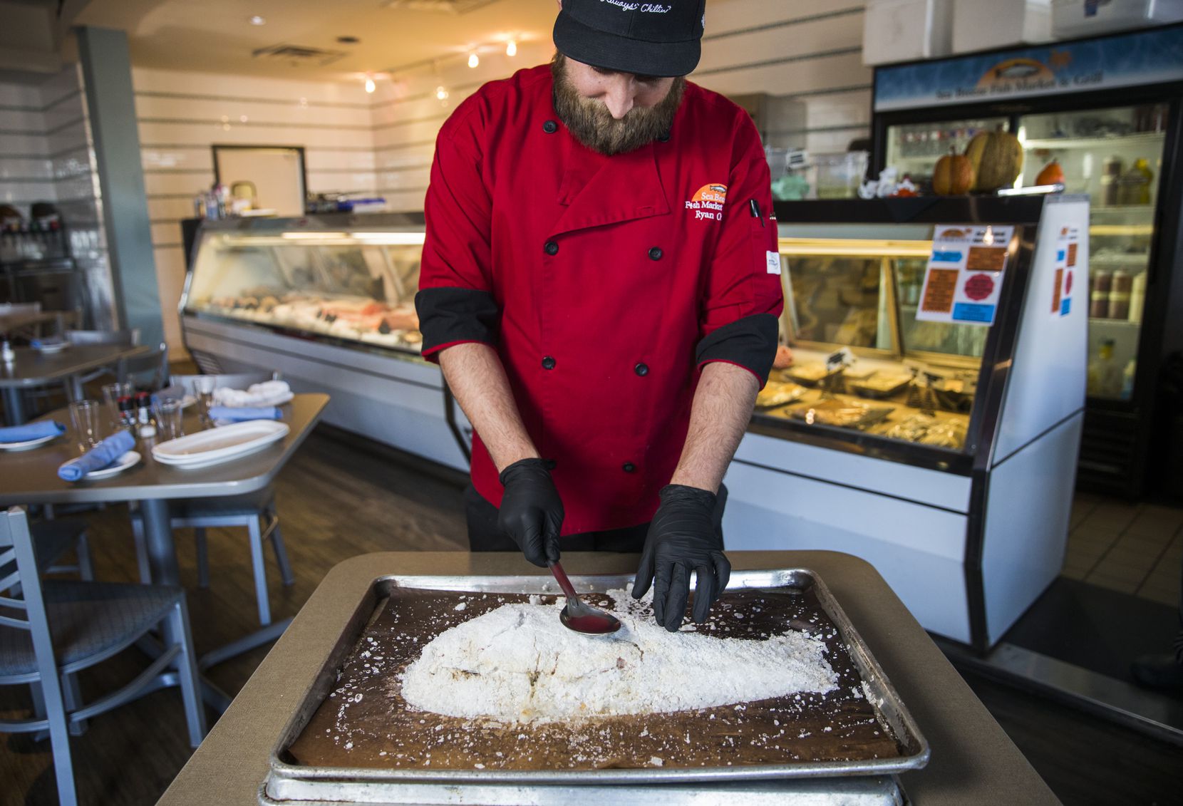 Chef and co-owner Ryan Oruch breaks into a baked Salt-Crusted Red Snapper dish at Sea Breeze...