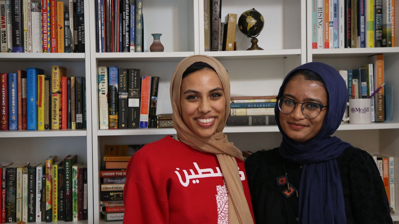 Amal and Manal Ahmed pose in front of a bookcase.