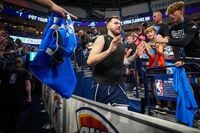 Dallas Mavericks fans reach out to guard Luka Doncic as he takes the court to warm up before...