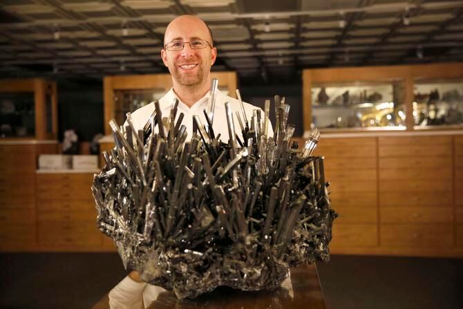 
Rob Lavinsky displays stibnite from China, a mineral with a metallic luster, at the...