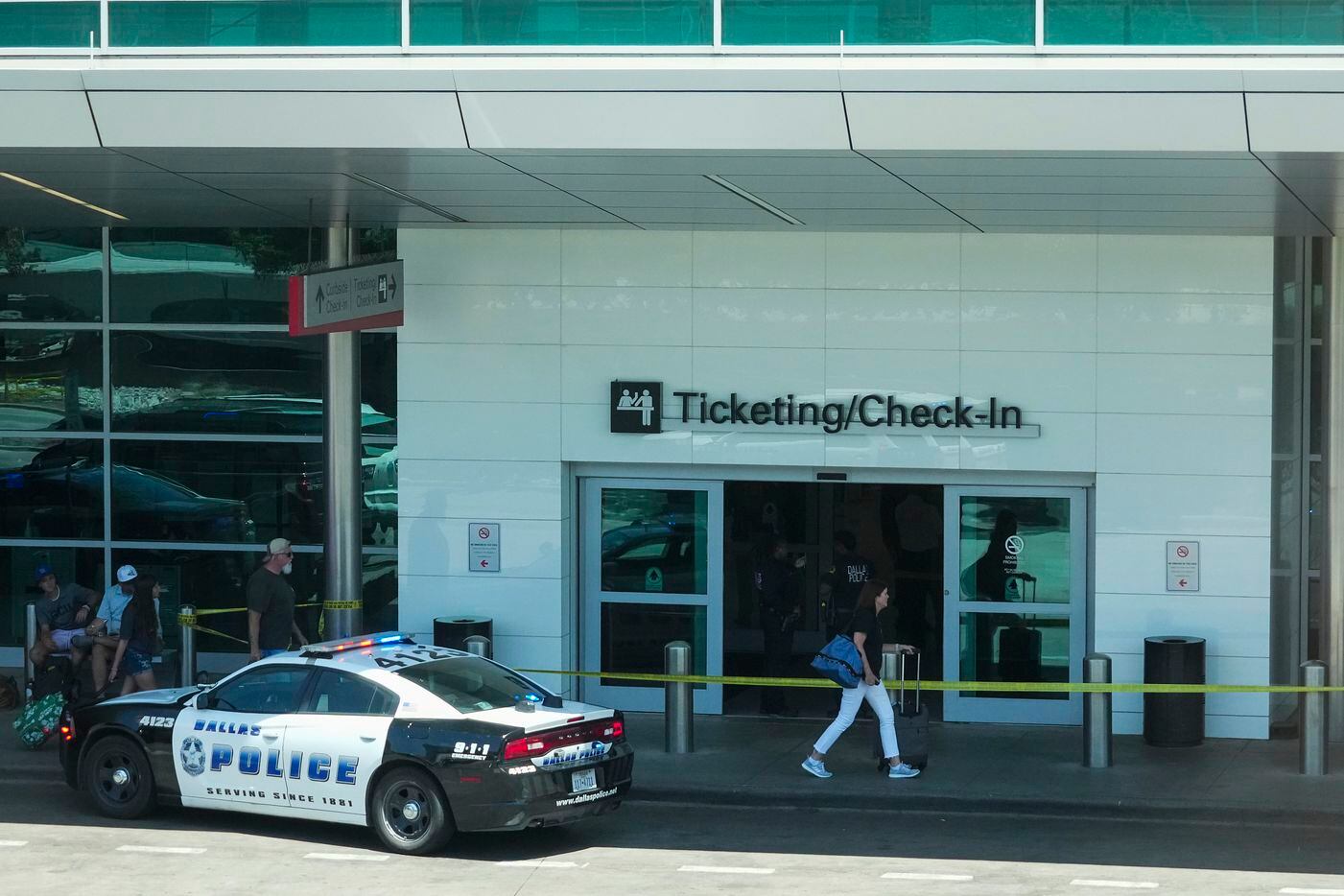 Passengers pass police tape as Dallas police investigate a scene Dallas Love Field Airport...