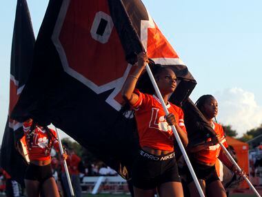 Lancaster trackster Kialia Claiborne, center, leads fellow track members as they run flags...