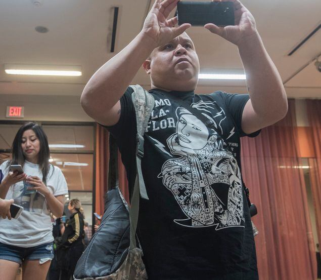 Wearing a shirt with an image of Selena Quintanilla-Pérez , Adrian Lopez takes a photo of a...