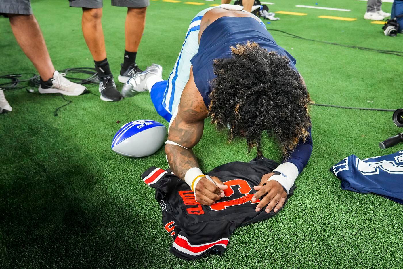 Dallas Cowboys running back Ezekiel Elliott autographs a jersey for a fan as he leaves the field following a victory over the Washington Football Team in an NFL football game at AT&T Stadium on Sunday, Dec. 26, 2021, in Arlington. The Cowboys won the game 56-14.