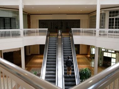 A man rides an escalator toward an empty storefront that used to be a Macy's at Collin Creek Mall in Plano.