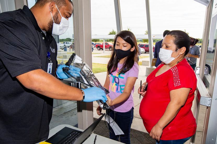 Tom Grau, (izq.), técnico del DISD, entrega un Chromebook a Kimberly Peña, una estudiante de...