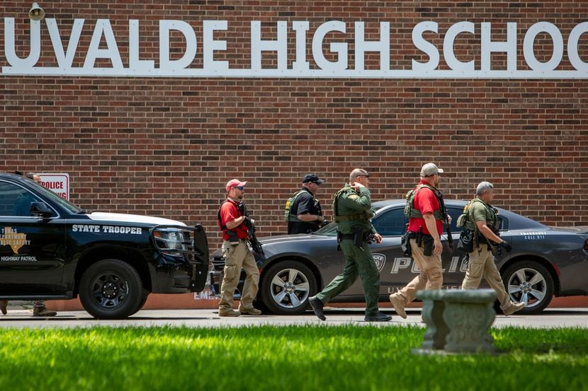 Law enforcement personnel walk outside Uvalde High School after shooting a was reported...