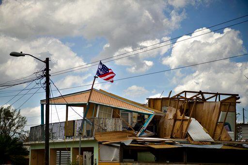 La bandera de un partido político ondea sobre una casa dañada por el paso del huracán María...