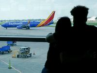 A couple watches as a Southwest Airlines flight taxis to the gate at Dallas Love Field.