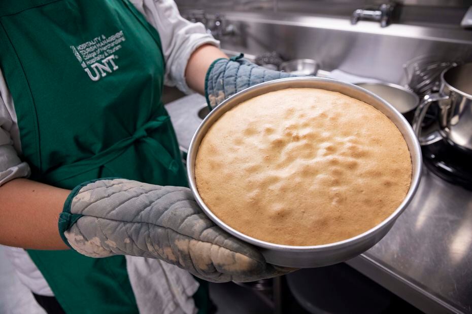 Junior Grace Harrison removes a genoise from the oven at the UNT culinary lab.